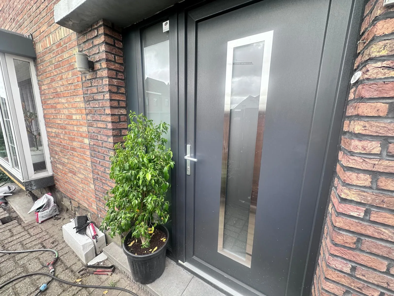 Donkere voordeur op bakstenen huisgevel