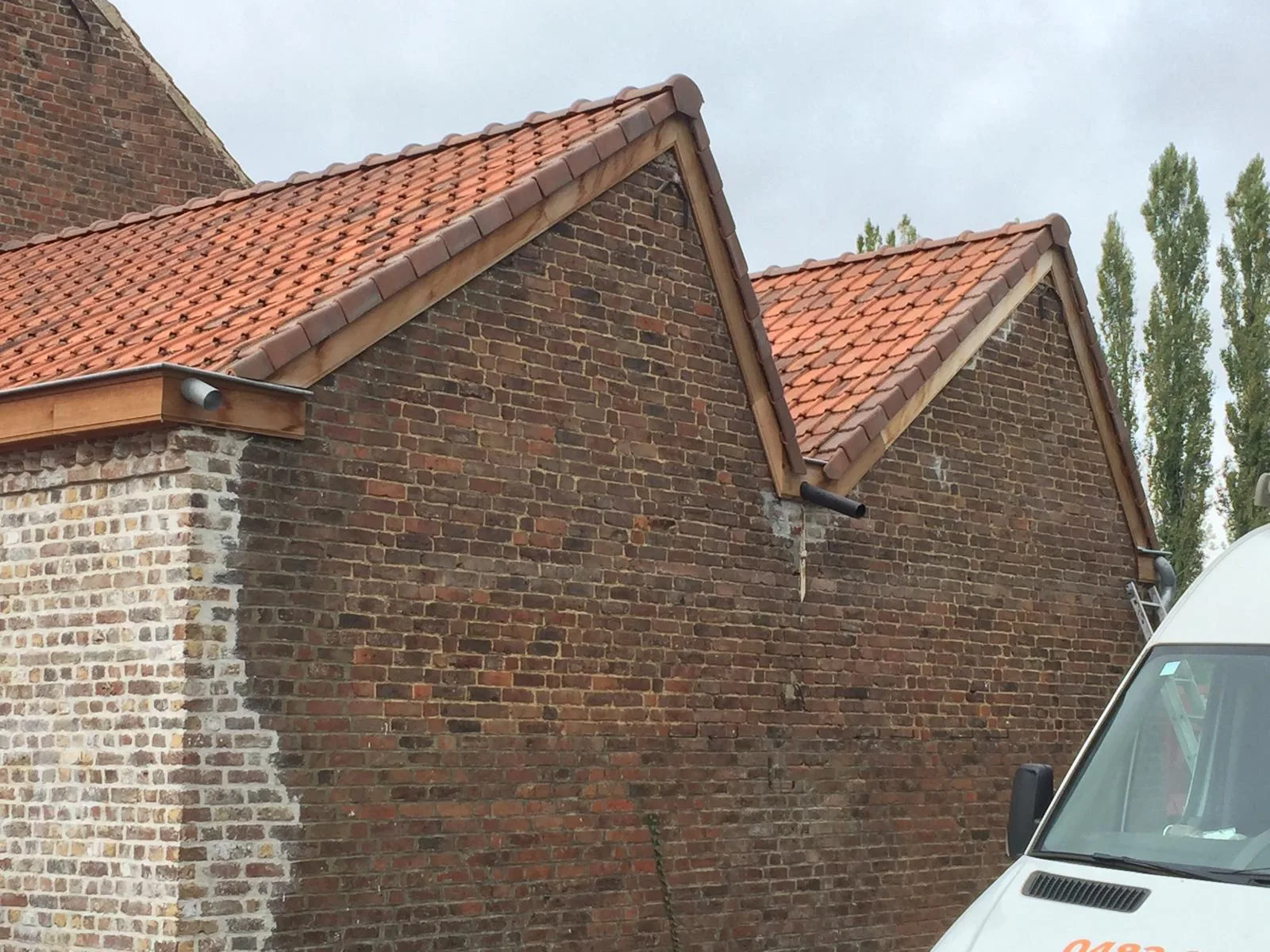 Gerenoveerd dak met terracotta tegels op baksteengebouw