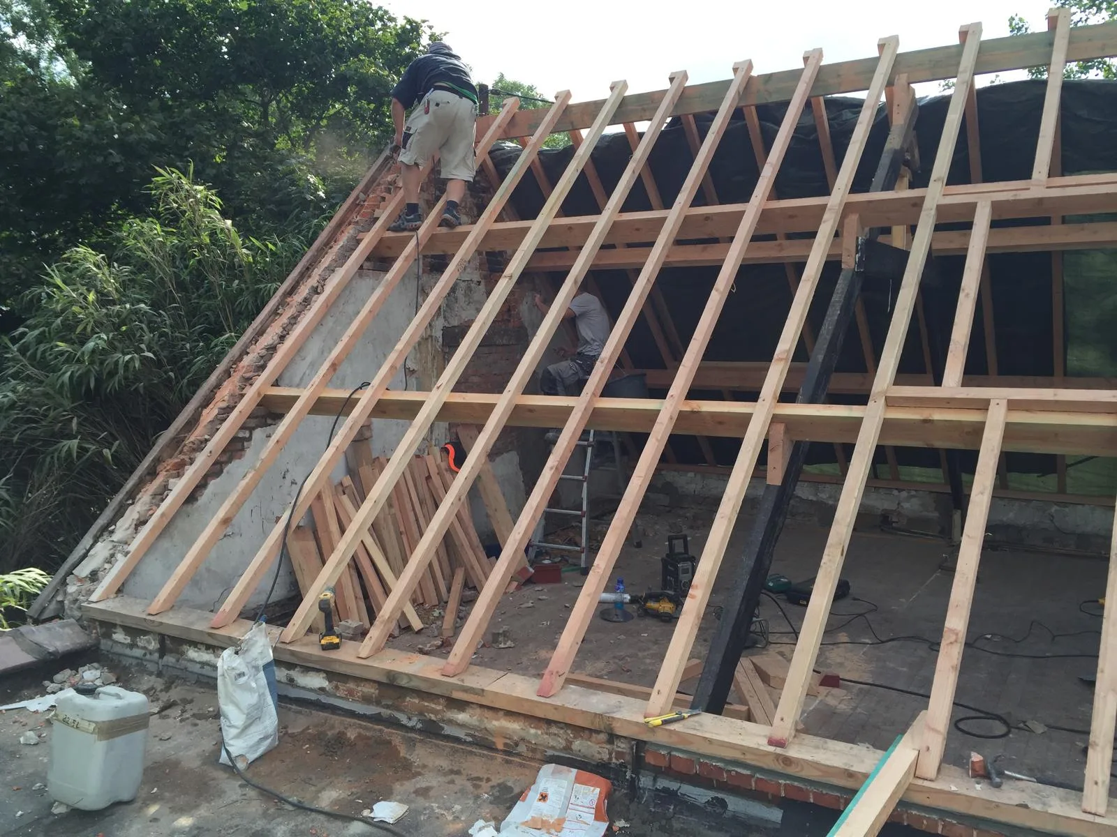 Werknemers aan het dak van een huis met houten constructie en bouwmaterialen