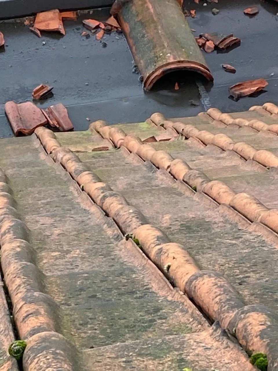 Dakreparatie met beschadigde dakpannen en een afvoerpijp op een hellend dak